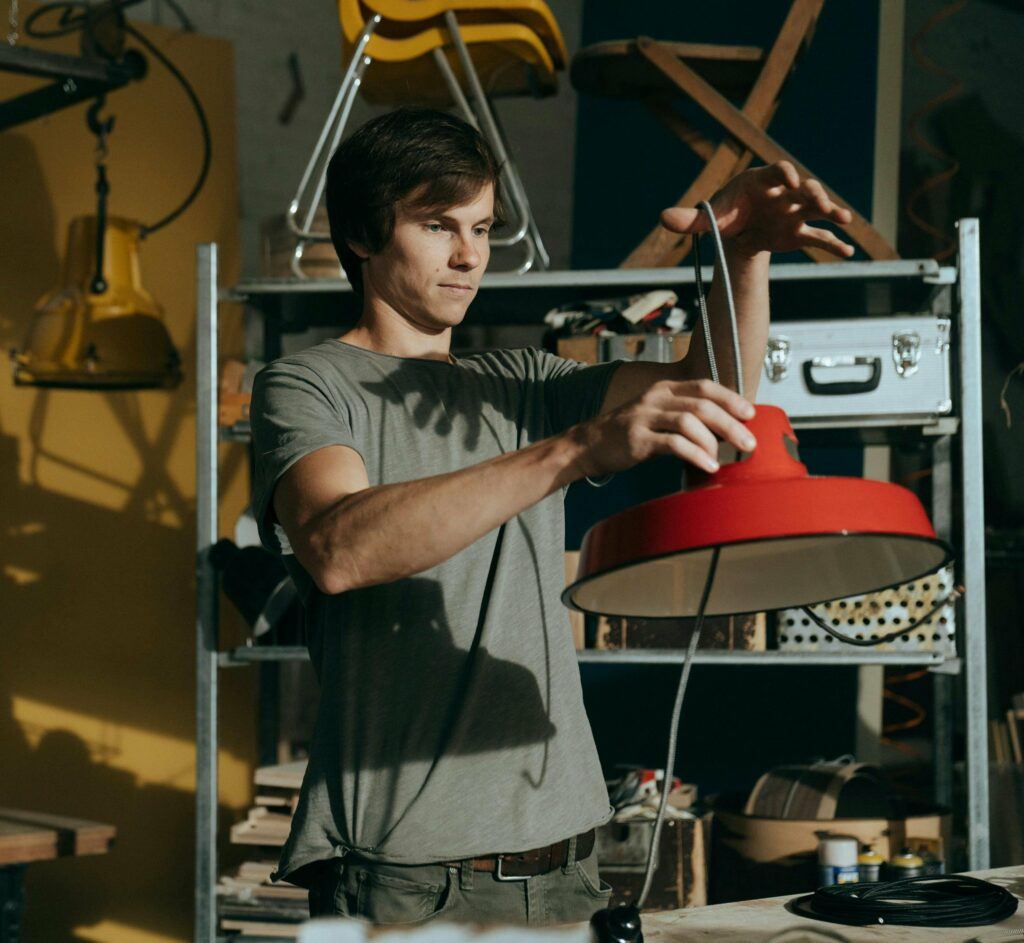 Man in a thrift store considering a red hanging light.